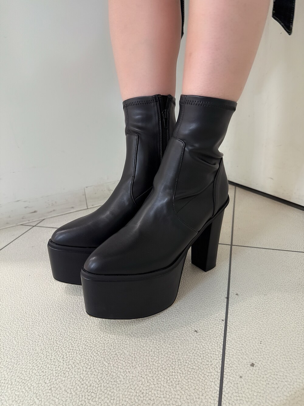 ブラック系のニット/セーター、ブラック系のデニムパンツ、ブラック系のブーツを着用したレディースの夏コーディネートの9枚目の写真