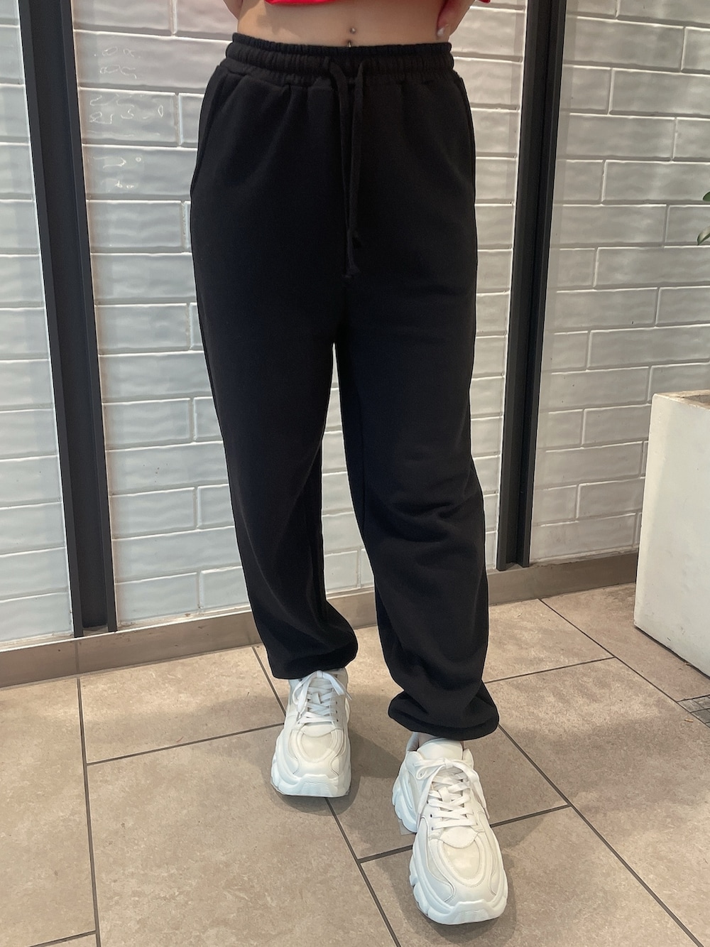 レッド系のTシャツ/カットソー、ブラック系のスウェットパンツ、ホワイト系のスニーカーを着用したレディースの夏コーディネートの7枚目の写真