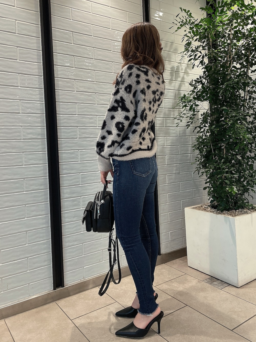 ホワイト系のニット/セーター、ブラック系のバックパック/リュック、ブラック系のパンプスを着用したレディースの冬コーディネートの3枚目の写真