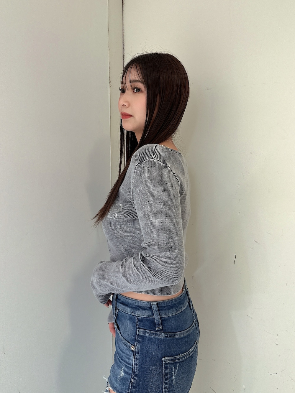 ブラック系のニット/セーター、ブルー系のデニムパンツ、ブラック系のサンダルを着用したレディースの春コーディネートの5枚目の写真