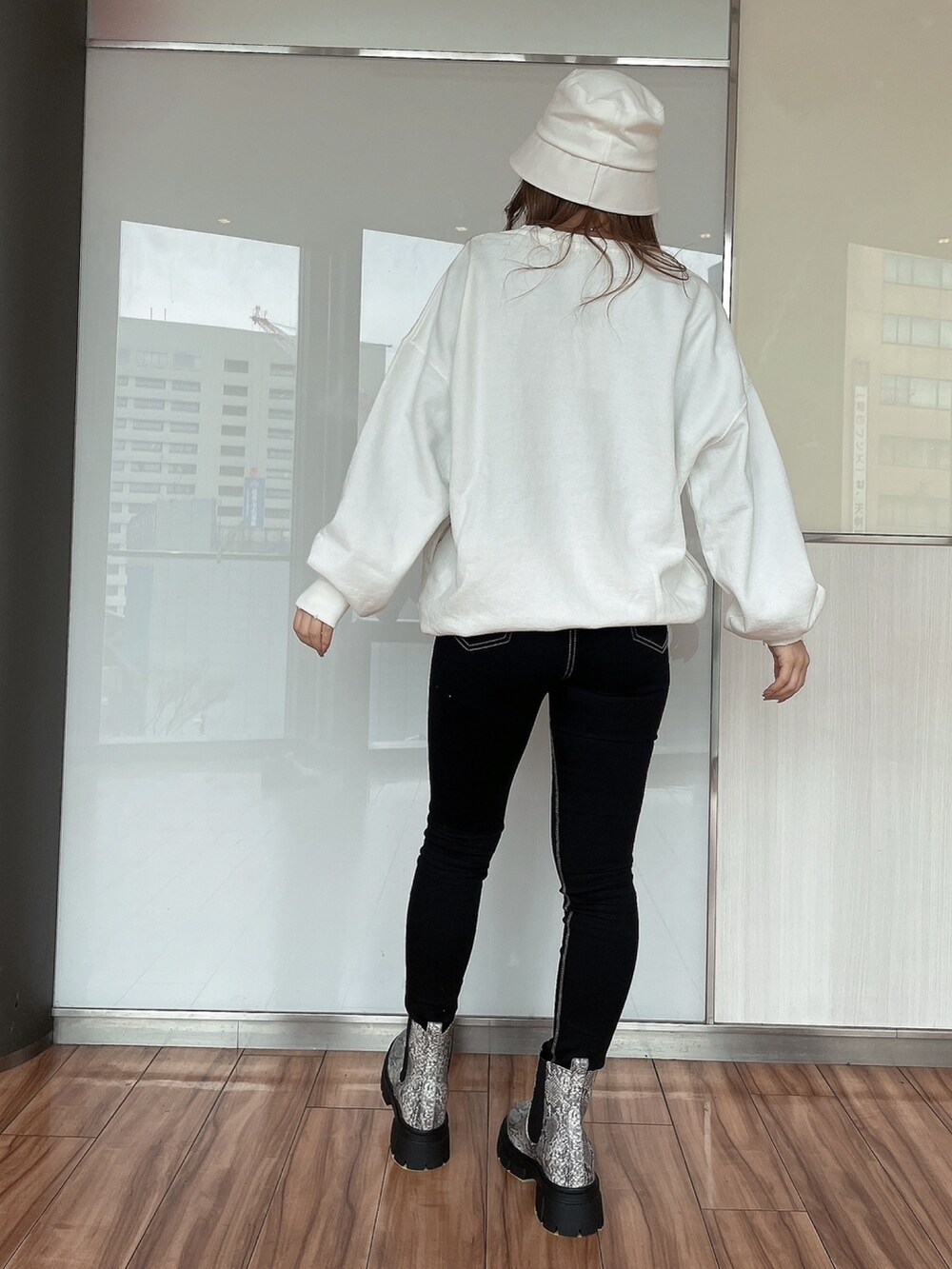 ホワイト系のスウェット、ブラック系のデニムパンツ、その他のブーツを着用したレディースの冬コーディネートの2枚目の写真