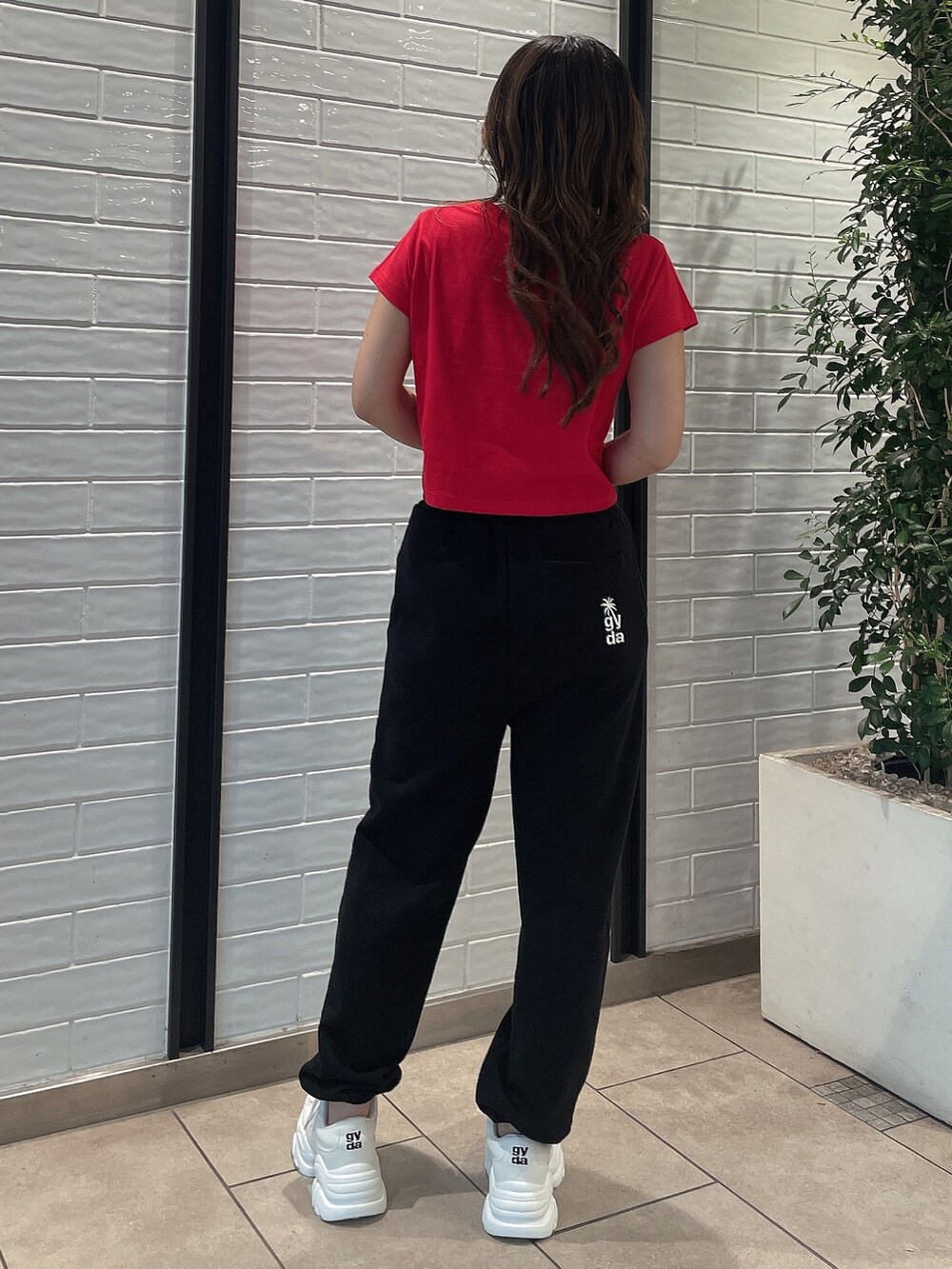 レッド系のTシャツ/カットソー、ブラック系のスウェットパンツ、ホワイト系のスニーカーを着用したレディースの夏コーディネートの3枚目の写真