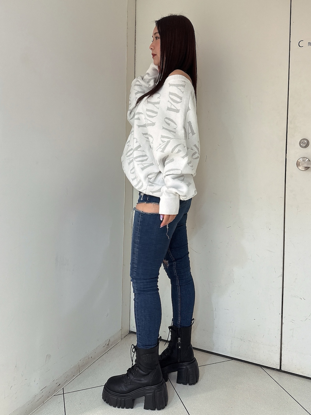 ホワイト系のニット/セーター、ブルー系のデニムパンツ、ブラック系のブーツを着用したレディースの秋コーディネートの2枚目の写真