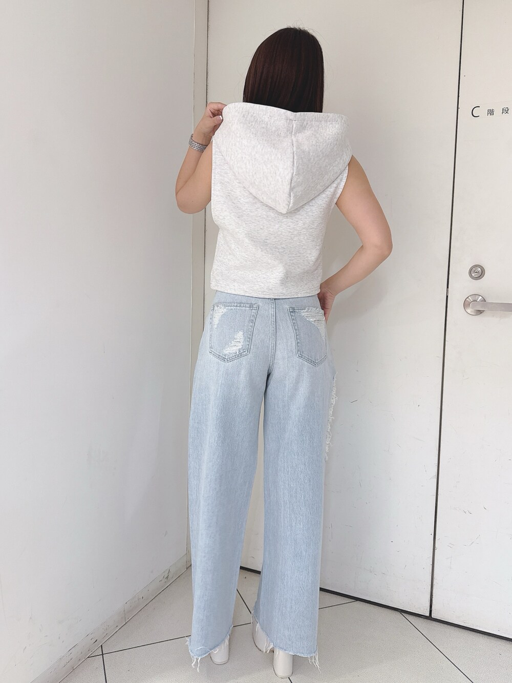 グレー系のパーカー、ブルー系のデニムパンツ、ホワイト系のサンダルを着用したレディースの夏コーディネートの3枚目の写真