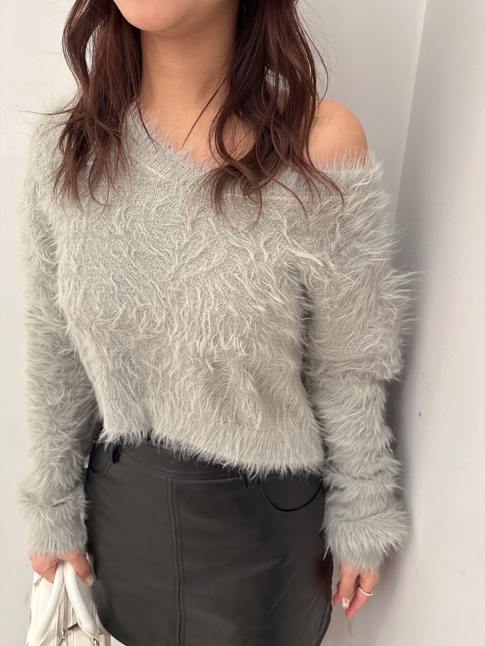 ブラック系のブーツ、ブラック系のスカート、ホワイト系のハンドバッグを着用したレディースの冬コーディネートの7枚目の写真