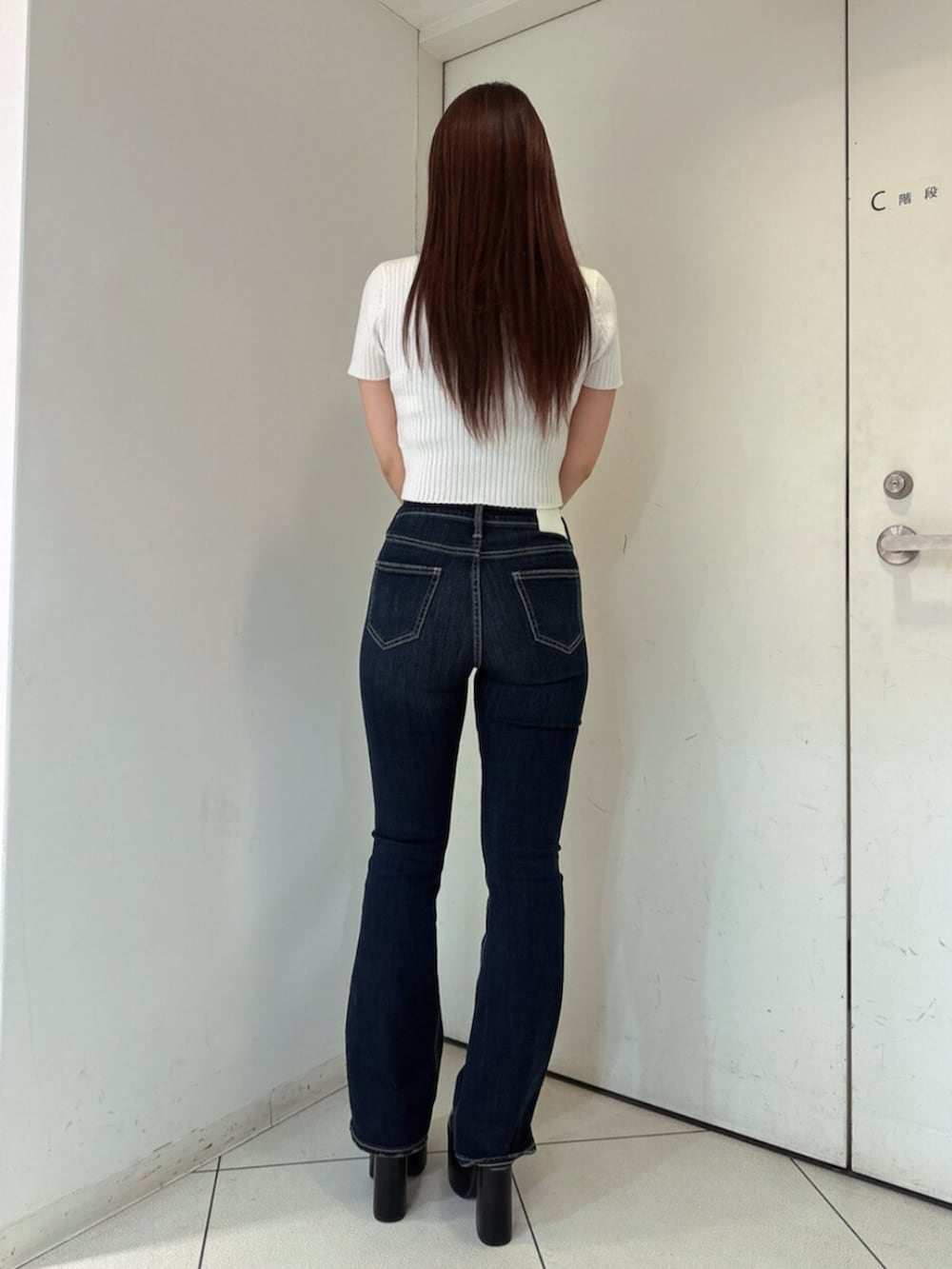 ブルー系のデニムパンツ、ブラック系のサンダル、ホワイト系のニット/セーターを着用したレディースの春コーディネートの3枚目の写真