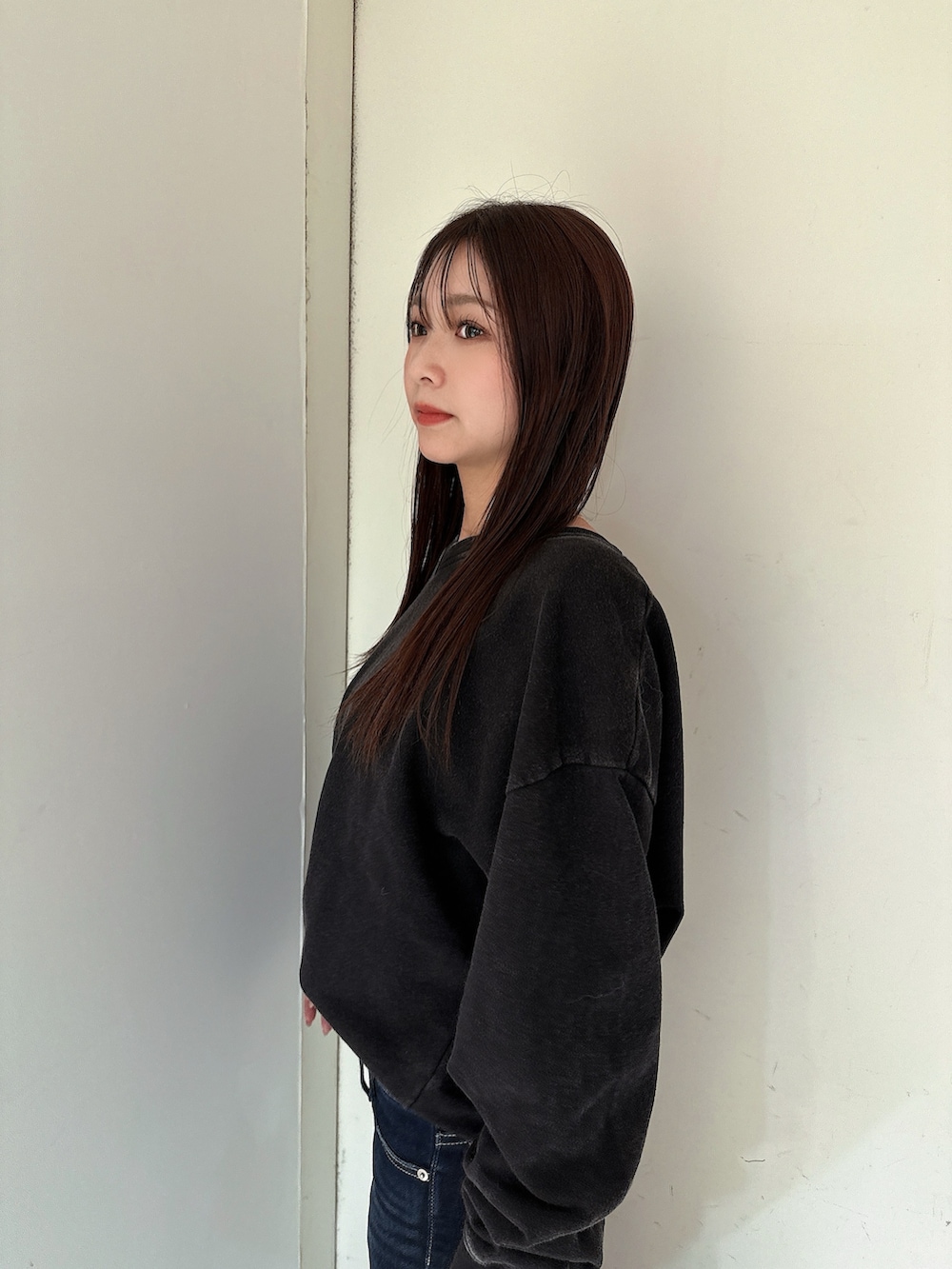 ブルー系のデニムパンツ、ブラック系のスウェット、ブラック系のブーツを着用したレディースの冬コーディネートの5枚目の写真