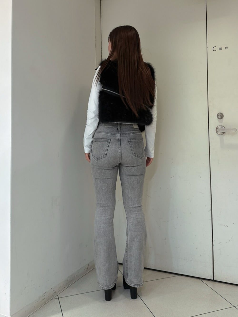 グレー系のデニムパンツ、ブラック系のブーツ、ブラック系のベストを着用したレディースの秋コーディネートの3枚目の写真
