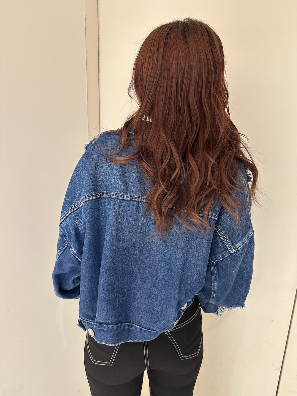 ブルー系のデニムジャケット、ブラック系のニット/セーター、ブラック系のデニムパンツを着用したレディースの春コーディネートの6枚目の写真