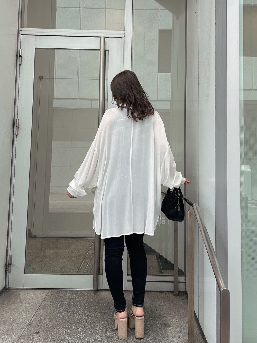 ホワイト系のサンダル、ブラック系のデニムパンツ、ブラック系のハンドバッグを着用したレディースの春コーディネートの2枚目の写真