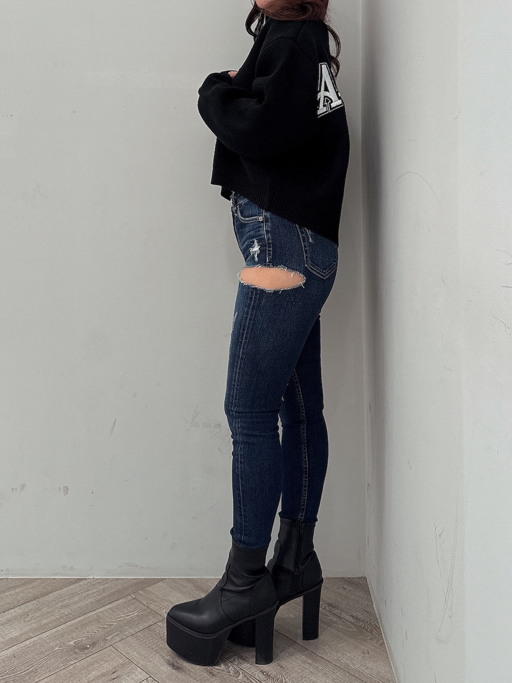 ブラック系のニット/セーター、ブルー系のデニムパンツ、ブラック系のブーツを着用したレディースの秋コーディネートの2枚目の写真