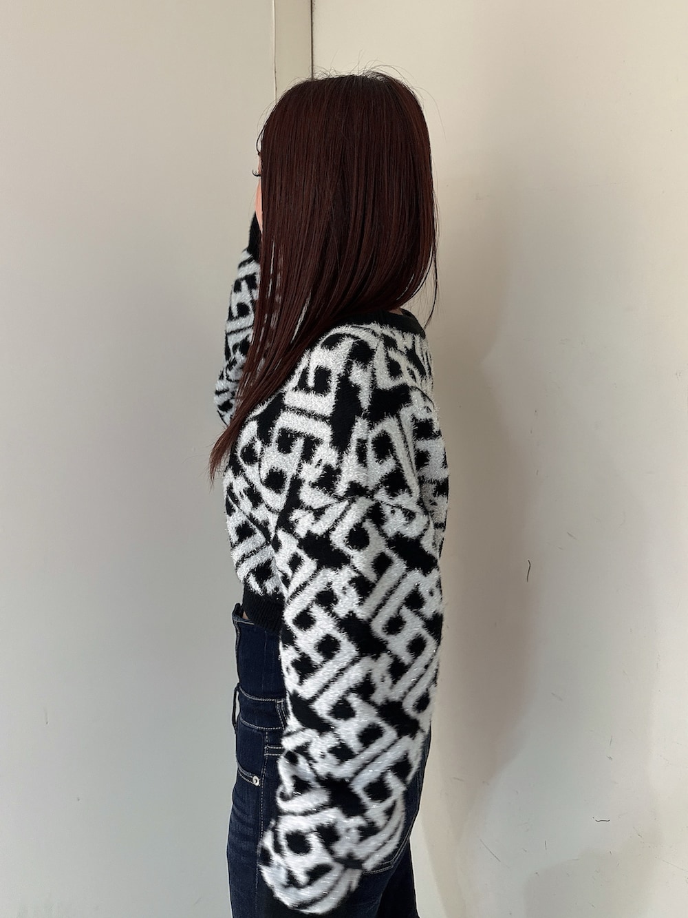 ブルー系のデニムパンツ、ブラック系のブーツ、ブラック系のニット/セーターを着用したレディースの秋コーディネートの5枚目の写真