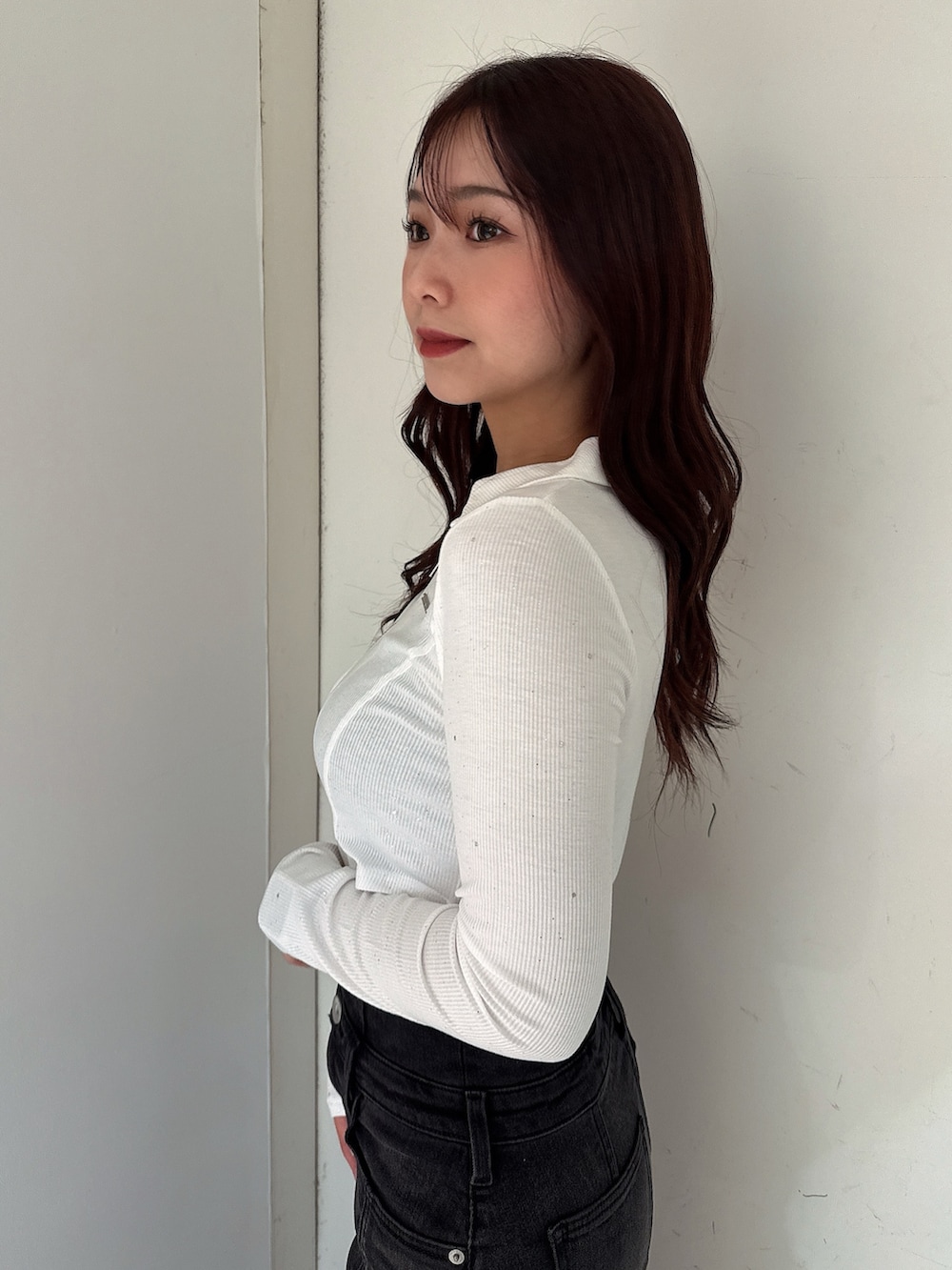 ブラック系のデニムスカート、ブラック系のTシャツ/カットソー、ホワイト系のパンプスを着用したレディースの秋コーディネートの5枚目の写真