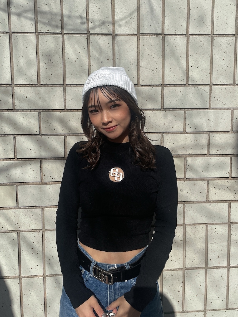 ブラック系のニット/セーター、ホワイト系のバックパック/リュック、ブルー系のデニムパンツを着用したレディースの冬コーディネートの3枚目の写真