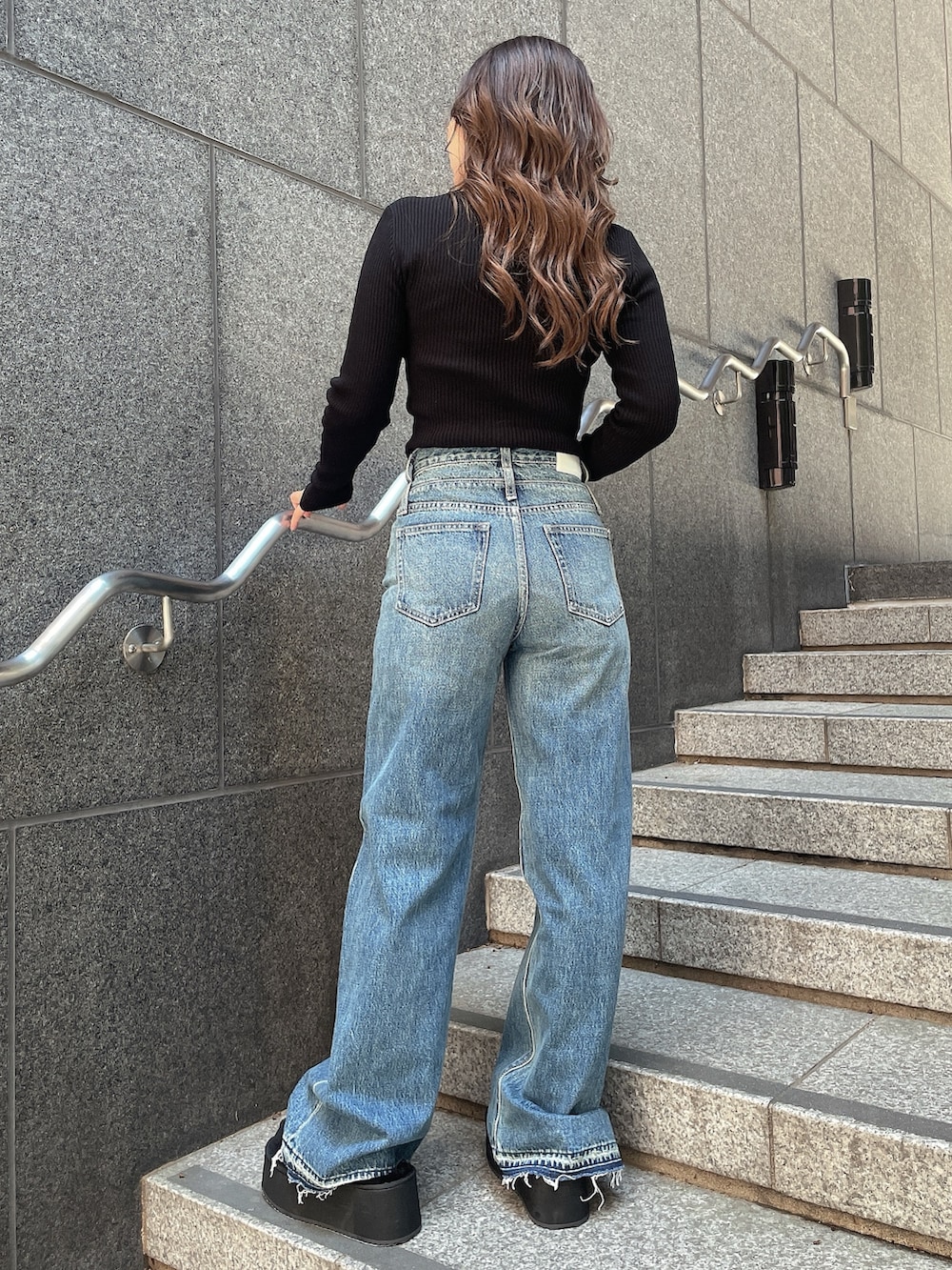 ブラック系のニット/セーター、ブルー系のデニムパンツ、ブラック系のスリッポンを着用したレディースの秋コーディネートの3枚目の写真