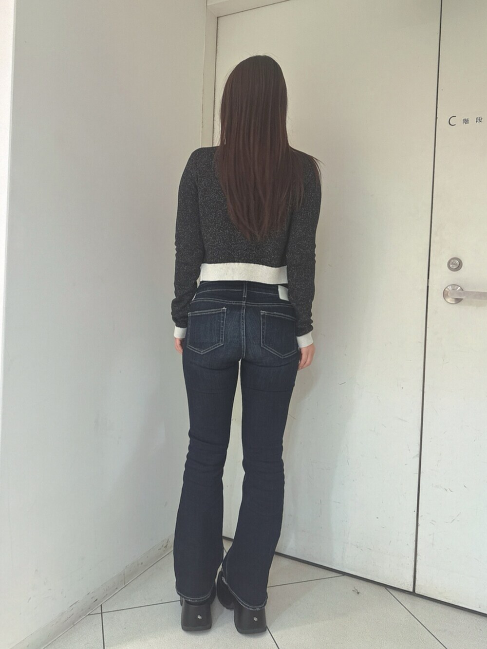 ブルー系のデニムパンツ、ブラック系のサンダル、ブラック系のニット/セーターを着用したレディースの春コーディネートの3枚目の写真