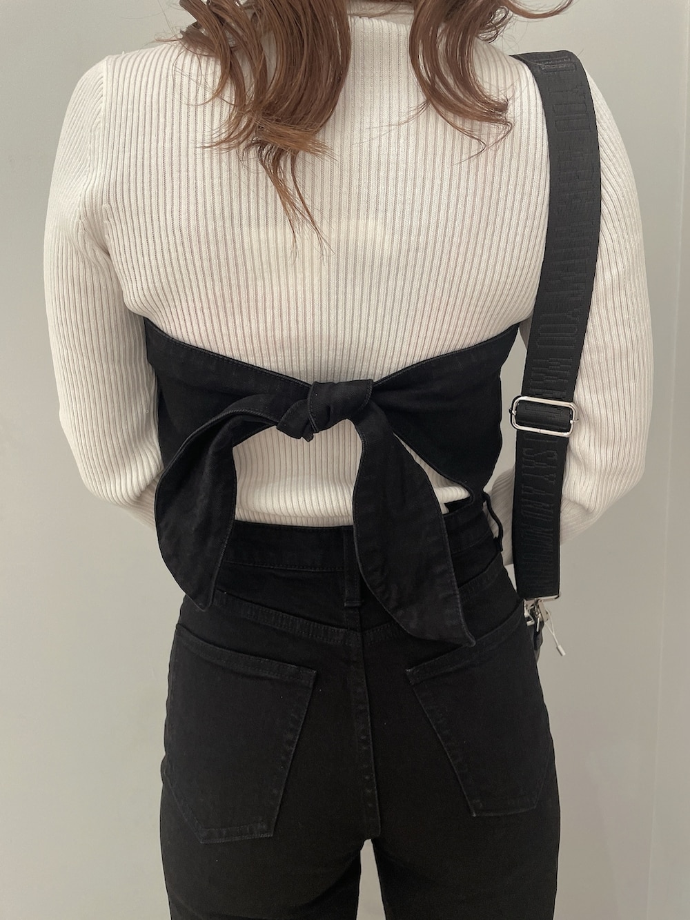 ホワイト系のニット/セーター、ブラック系のサロペット/オーバーオール、ブラック系のハンドバッグを着用したレディースの冬コーディネートの7枚目の写真