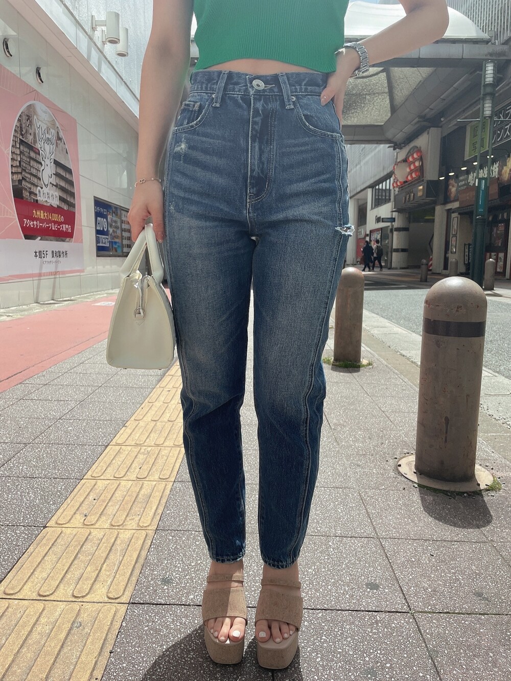 グリーン系のニット/セーター、ブルー系のデニムパンツ、ホワイト系のハンドバッグを着用したレディースの春コーディネートの6枚目の写真