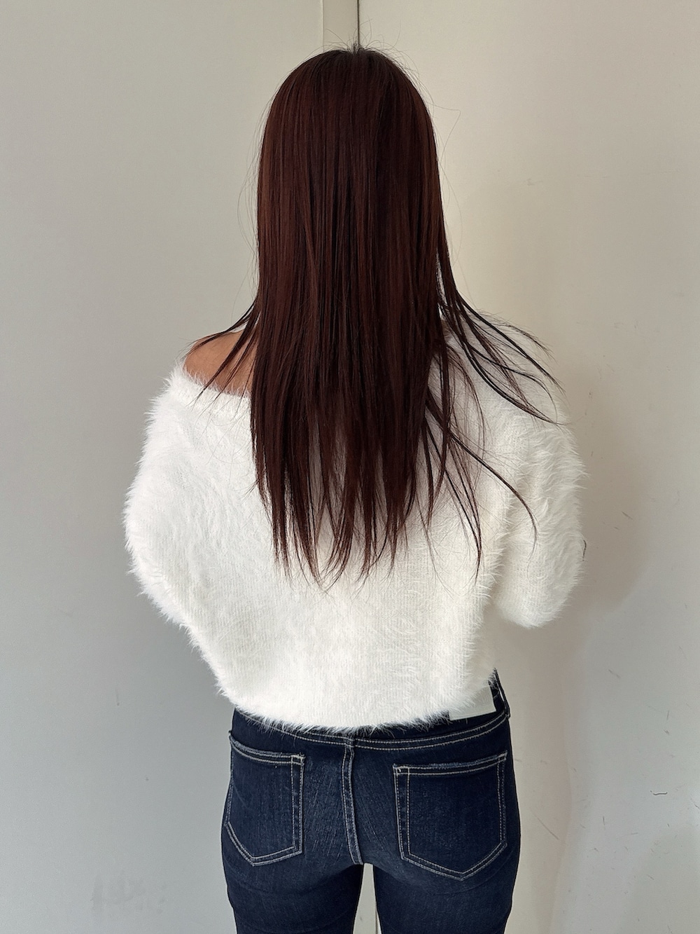 ブルー系のデニムパンツ、ブラック系のブーツ、ホワイト系のニット/セーターを着用したレディースの秋コーディネートの6枚目の写真