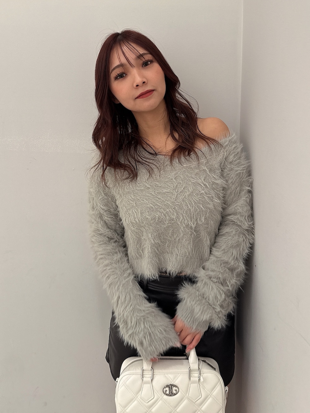 ブラック系のブーツ、ブラック系のスカート、ホワイト系のハンドバッグを着用したレディースの冬コーディネートの4枚目の写真