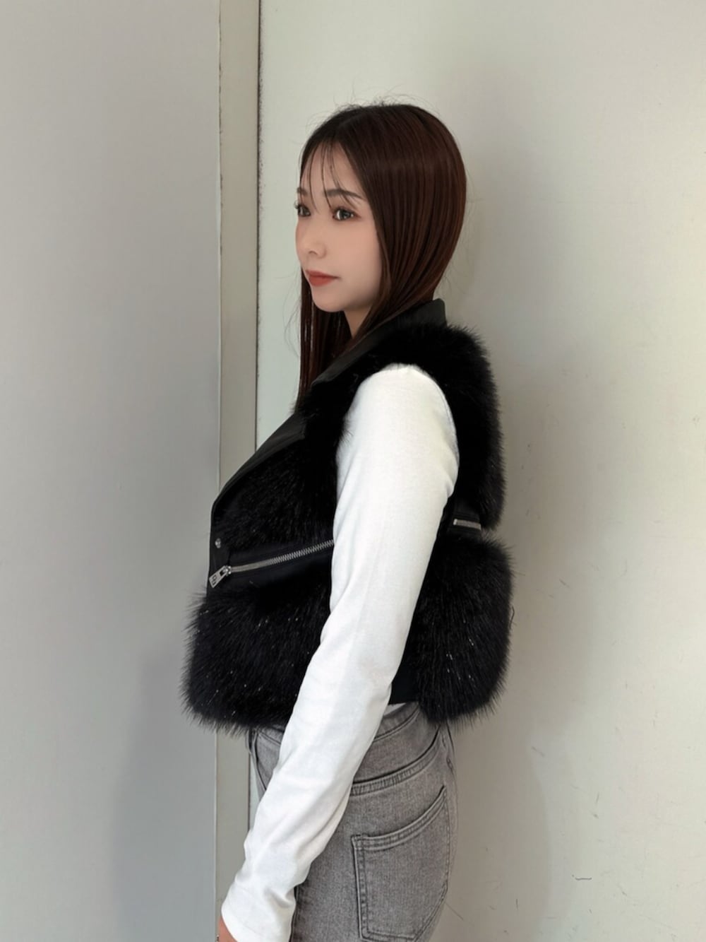 グレー系のデニムパンツ、ブラック系のブーツ、ブラック系のベストを着用したレディースの秋コーディネートの5枚目の写真