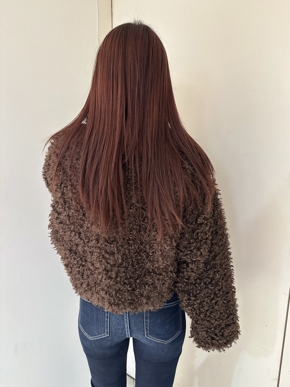 ブルー系のデニムパンツ、ブラック系のブーツ、ブラウン系のブルゾンを着用したレディースの秋コーディネートの6枚目の写真