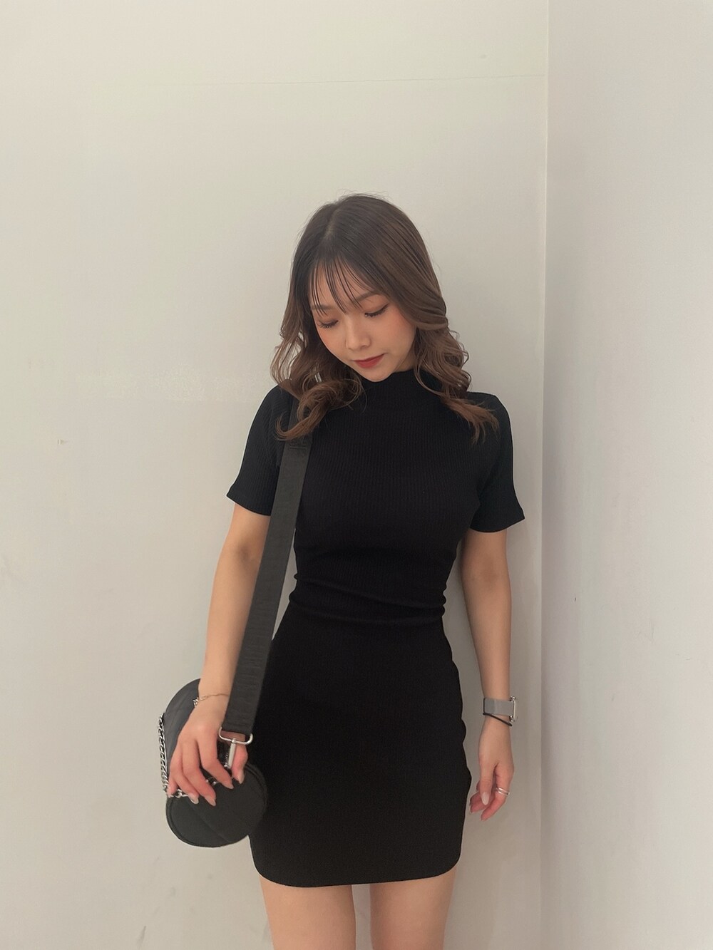 ブラック系のハンドバッグ、ブラック系のブーツ、ブラック系のワンピースを着用したレディースの冬コーディネートの4枚目の写真