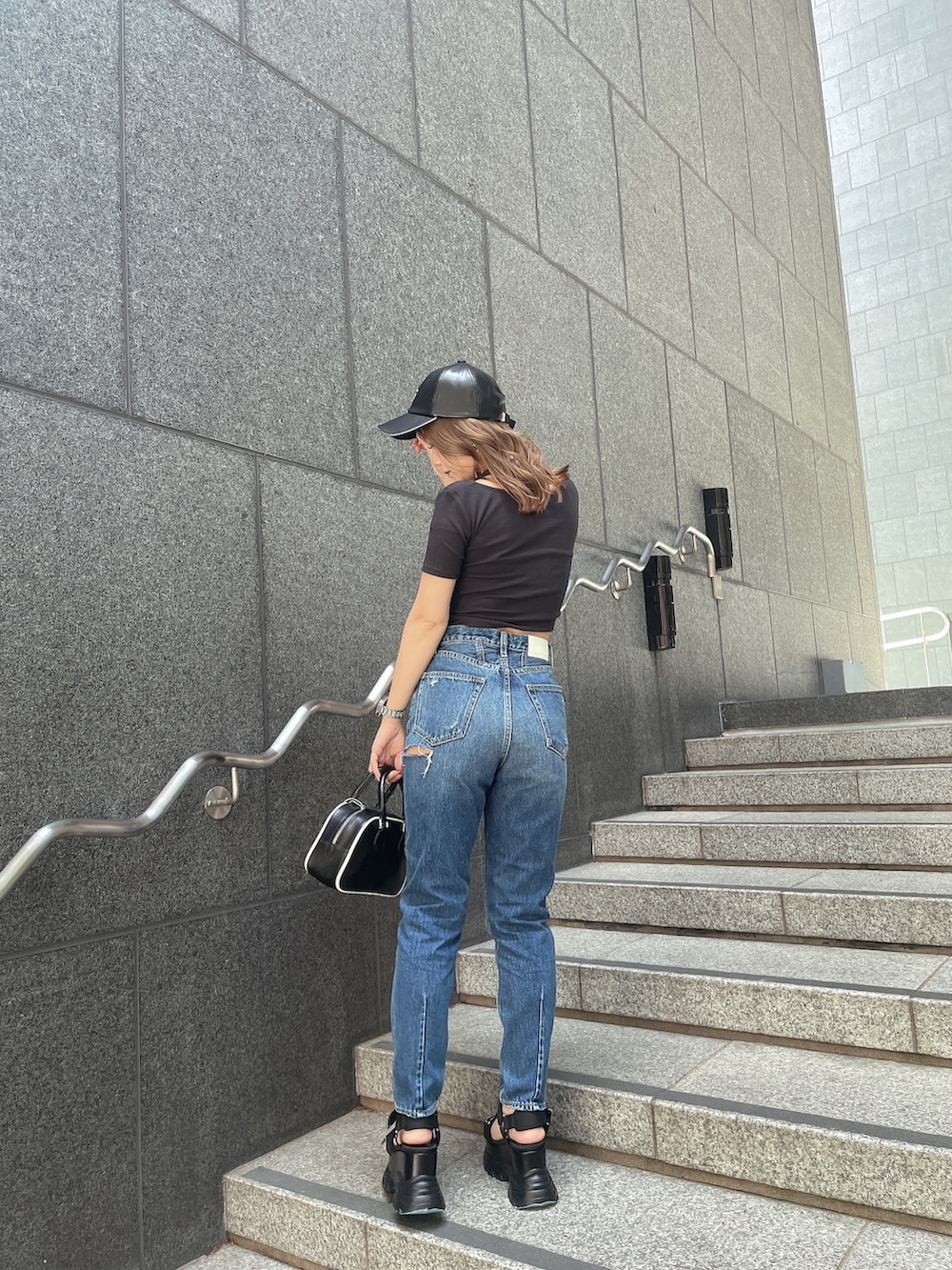 ブラック系のTシャツ/カットソー、ブルー系のデニムパンツ、ブラック系のサンダルを着用したレディースの春コーディネートの2枚目の写真