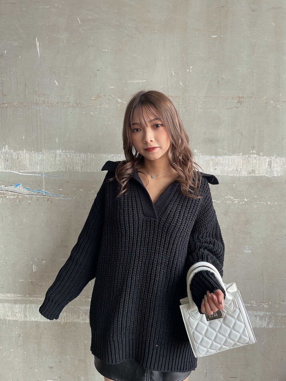 ブラック系のニット/セーター、ホワイト系のハンドバッグ、ブラック系のスカートを着用したレディースの秋コーディネートの4枚目の写真