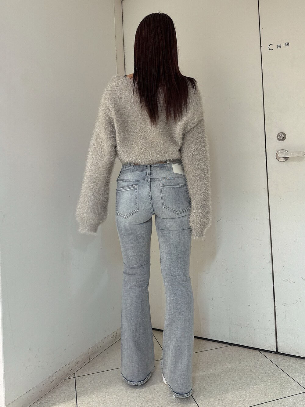 ブルー系のデニムパンツ、ホワイト系のパンプス、ベージュ系のカーディガン/ボレロを着用したレディースの秋コーディネートの3枚目の写真