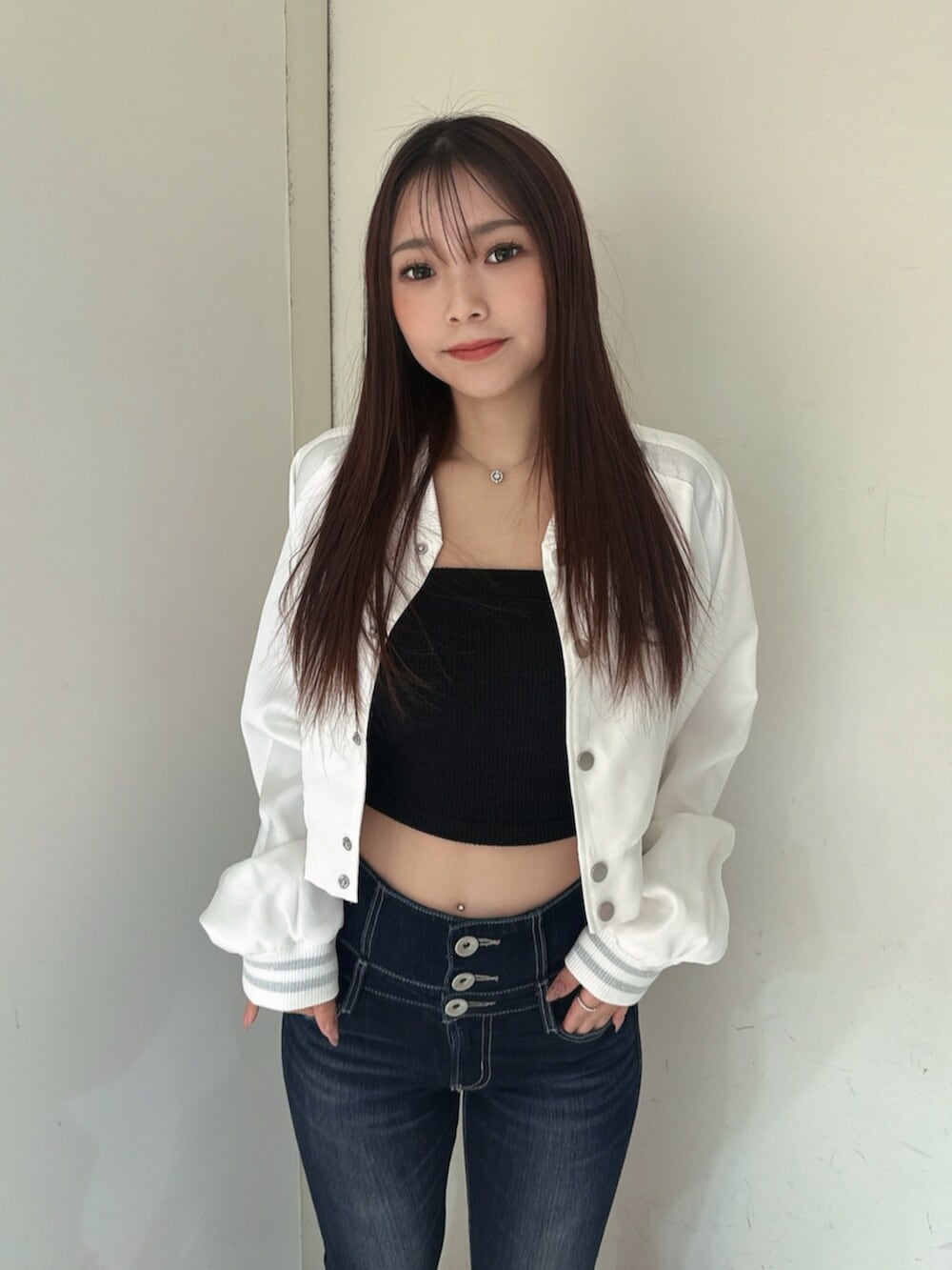 ブルー系のデニムパンツ、ブラック系のサンダル、ホワイト系のブルゾンを着用したレディースの春コーディネートの4枚目の写真