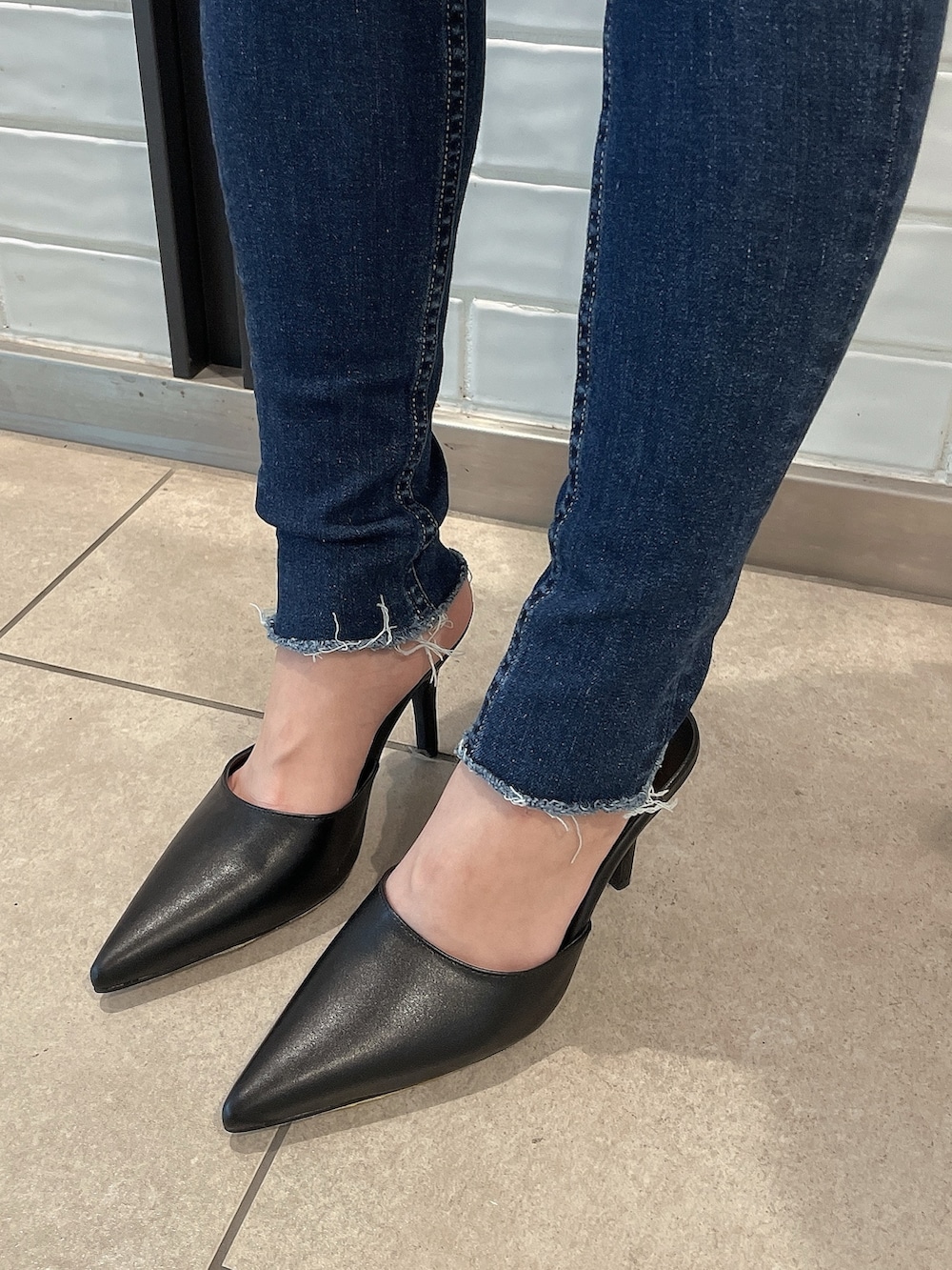 ホワイト系のニット/セーター、ブラック系のバックパック/リュック、ブラック系のパンプスを着用したレディースの冬コーディネートの9枚目の写真