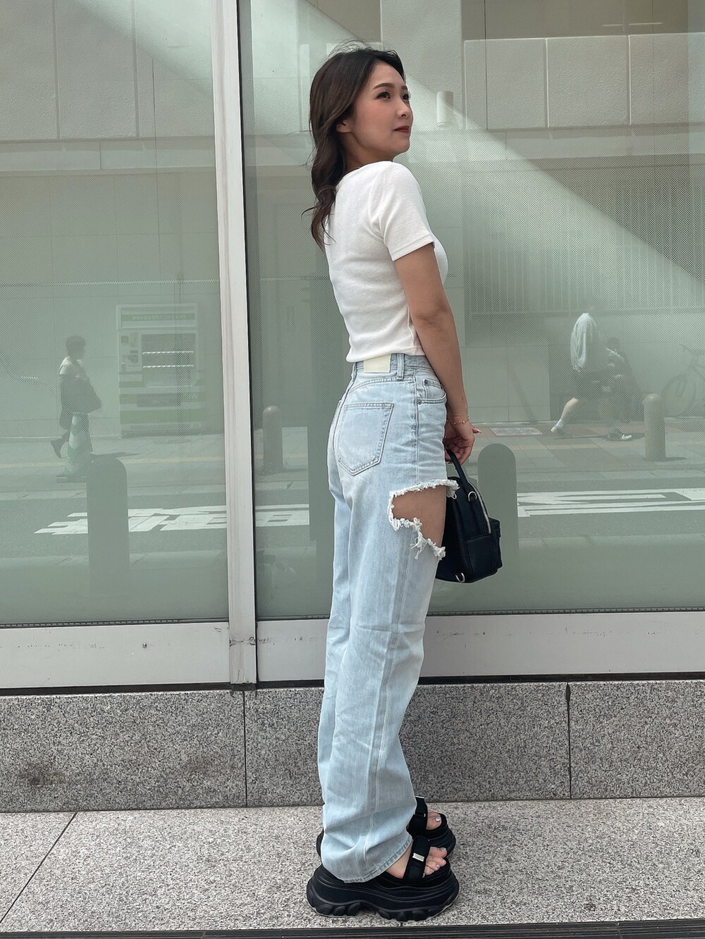 ホワイト系のTシャツ/カットソー、ブルー系のデニムパンツ、ブラック系のバックパック/リュックを着用したレディースの春コーディネートの2枚目の写真