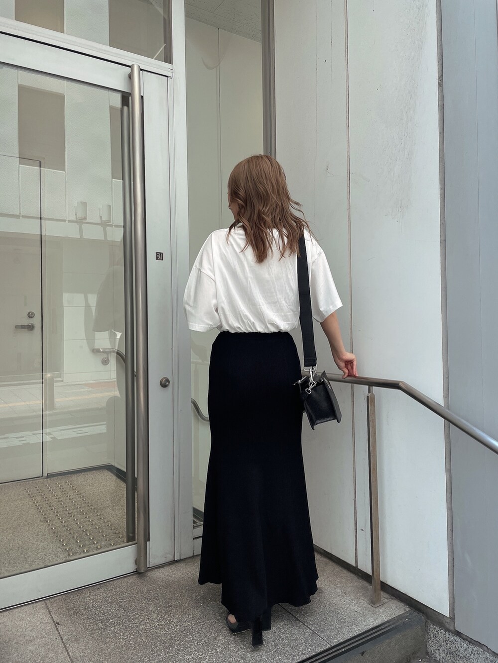 ブラック系のスカート、ブラック系のハンドバッグ、ホワイト系のTシャツ/カットソーを着用したレディースの夏コーディネートの4枚目の写真