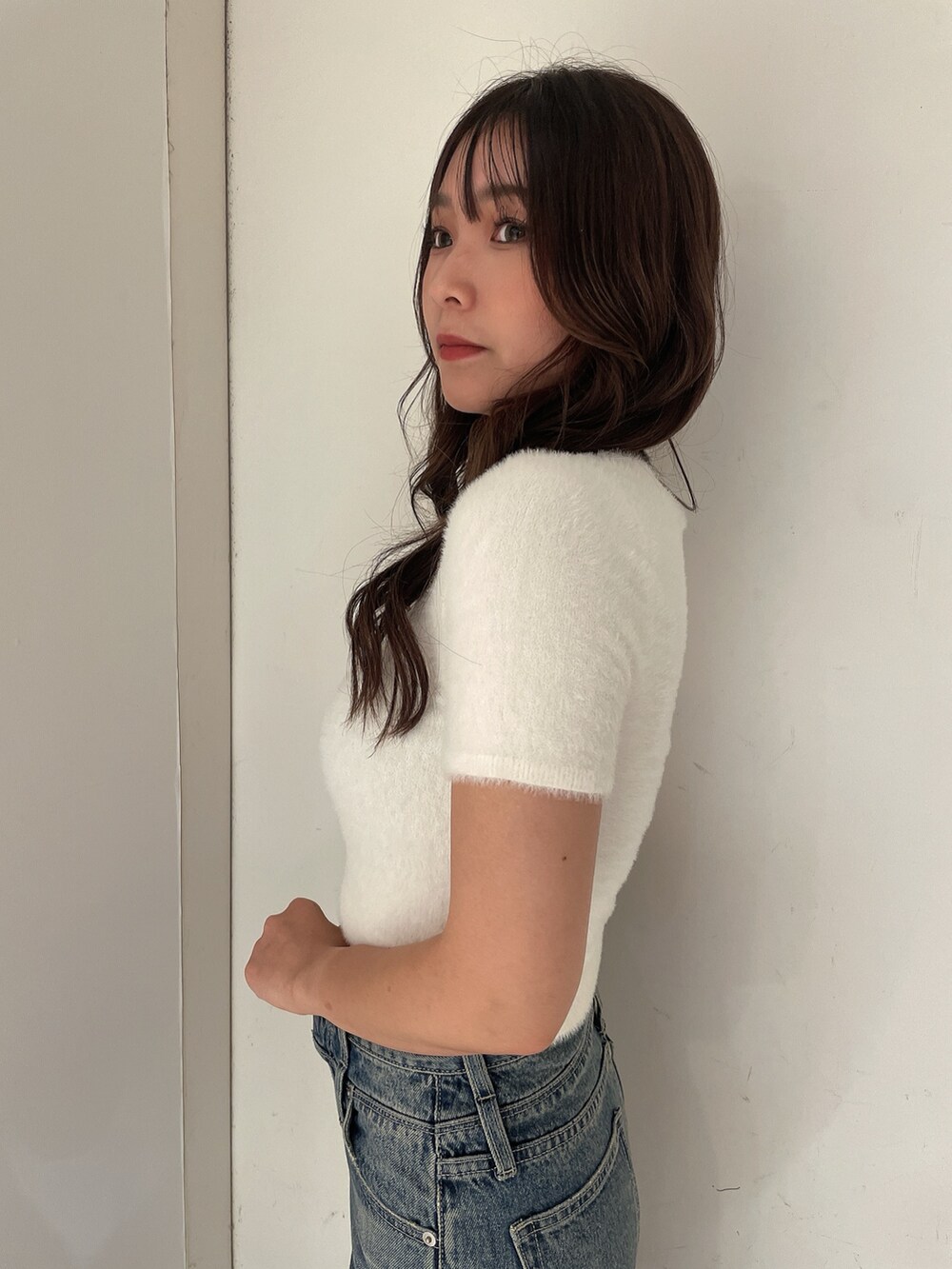 ホワイト系のニット/セーター、ブルー系のデニムパンツ、ベージュ系のスリッポンを着用したレディースの夏コーディネートの5枚目の写真