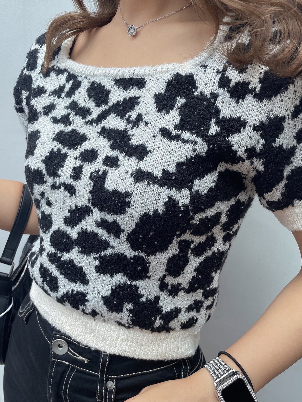 ホワイト系のニット/セーター、ブラック系のデニムパンツ、ブラック系のサンダルを着用したレディースの夏コーディネートの6枚目の写真