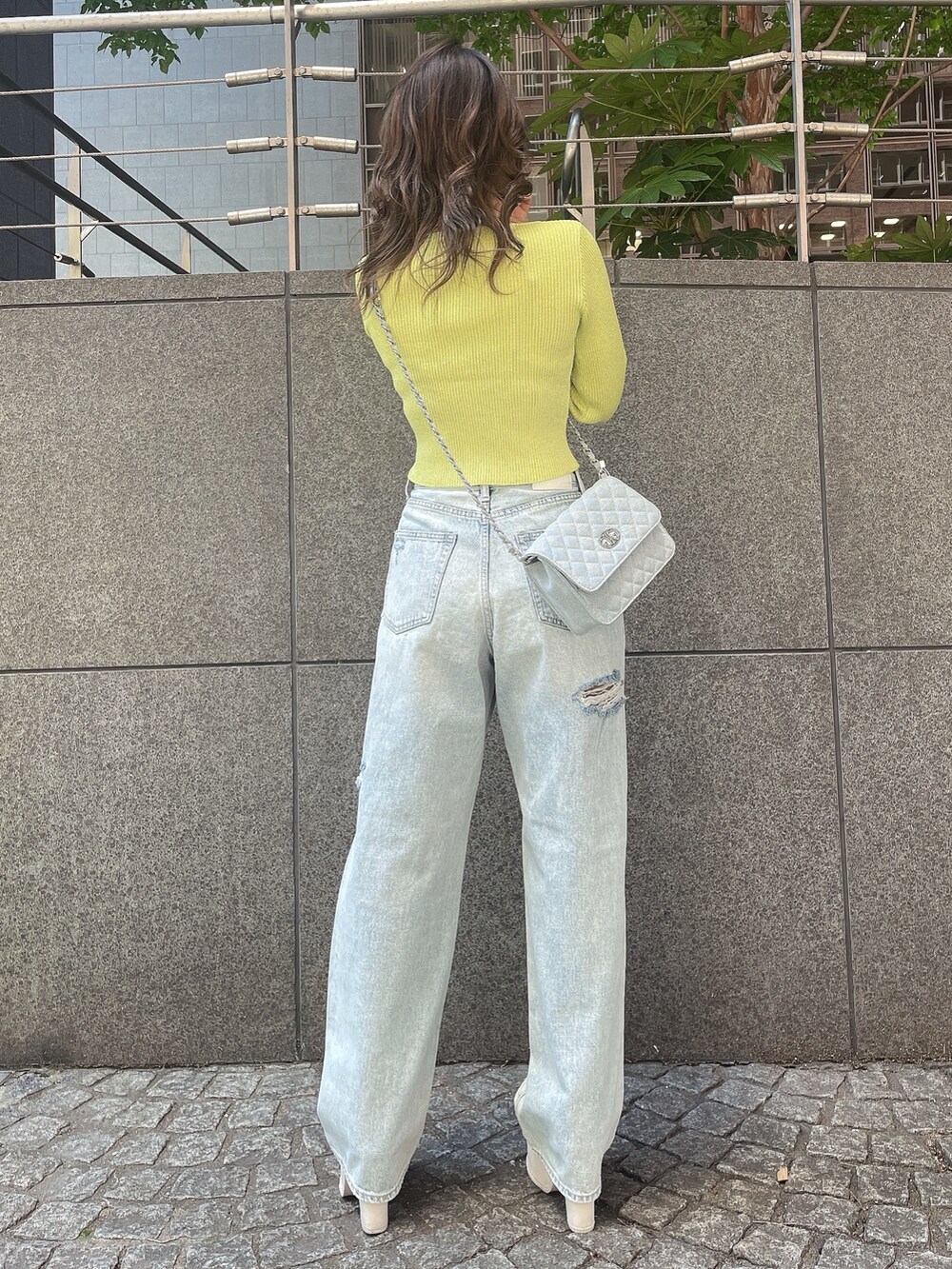 ブルー系のデニムパンツ、ホワイト系のサンダルを着用したレディースの春コーディネートの2枚目の写真