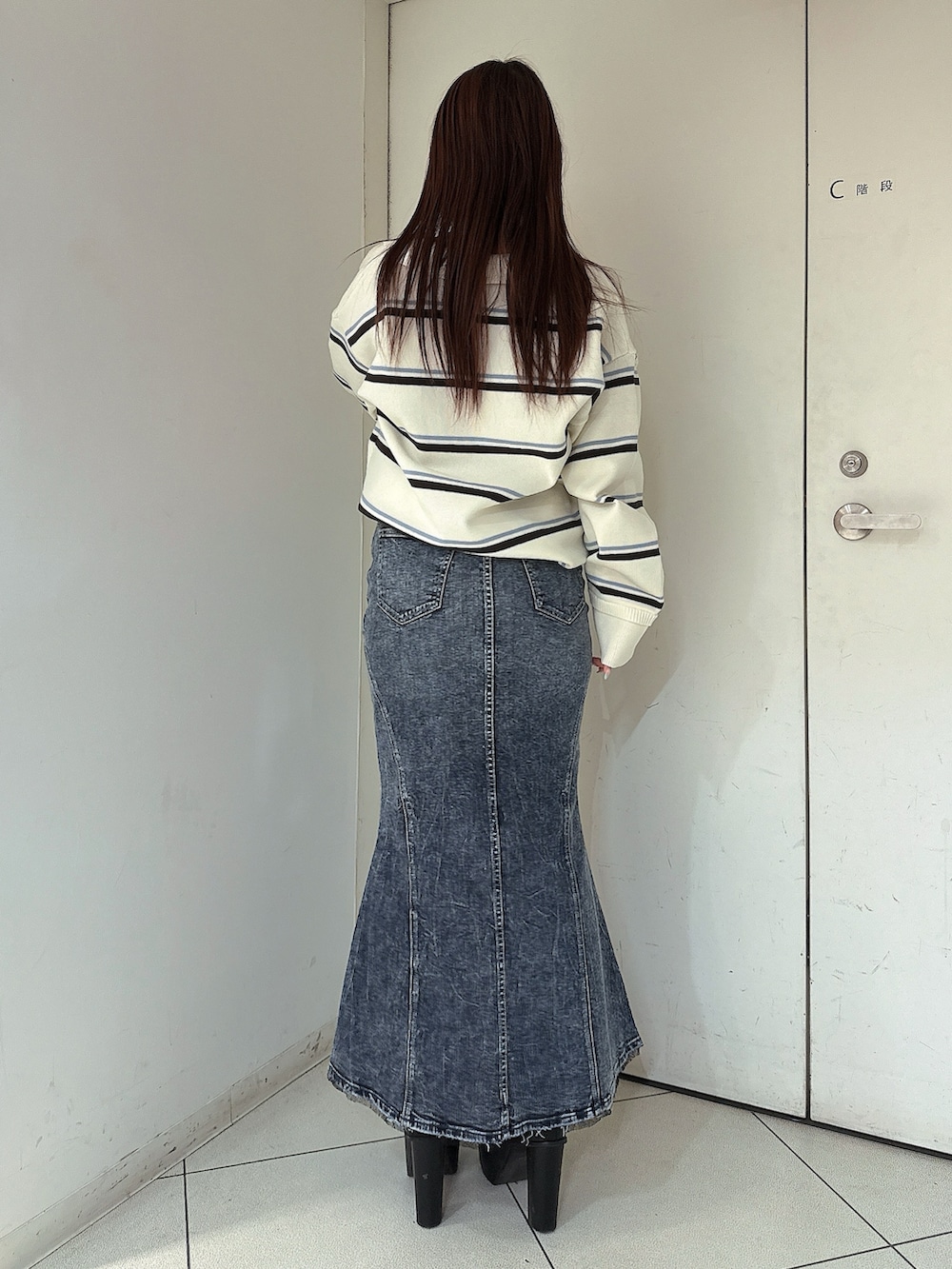 ブラック系のブーツ、ホワイト系のニット/セーター、ブルー系のデニムスカートを着用したレディースの冬コーディネートの3枚目の写真