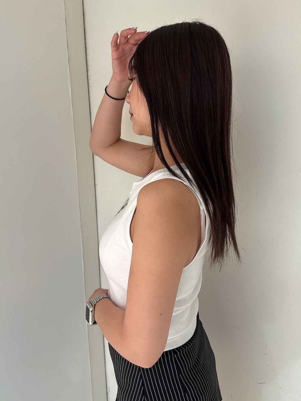 ブラック系のスカート、ホワイト系のタンクトップ、ブラック系のサンダルを着用したレディースの夏コーディネートの5枚目の写真