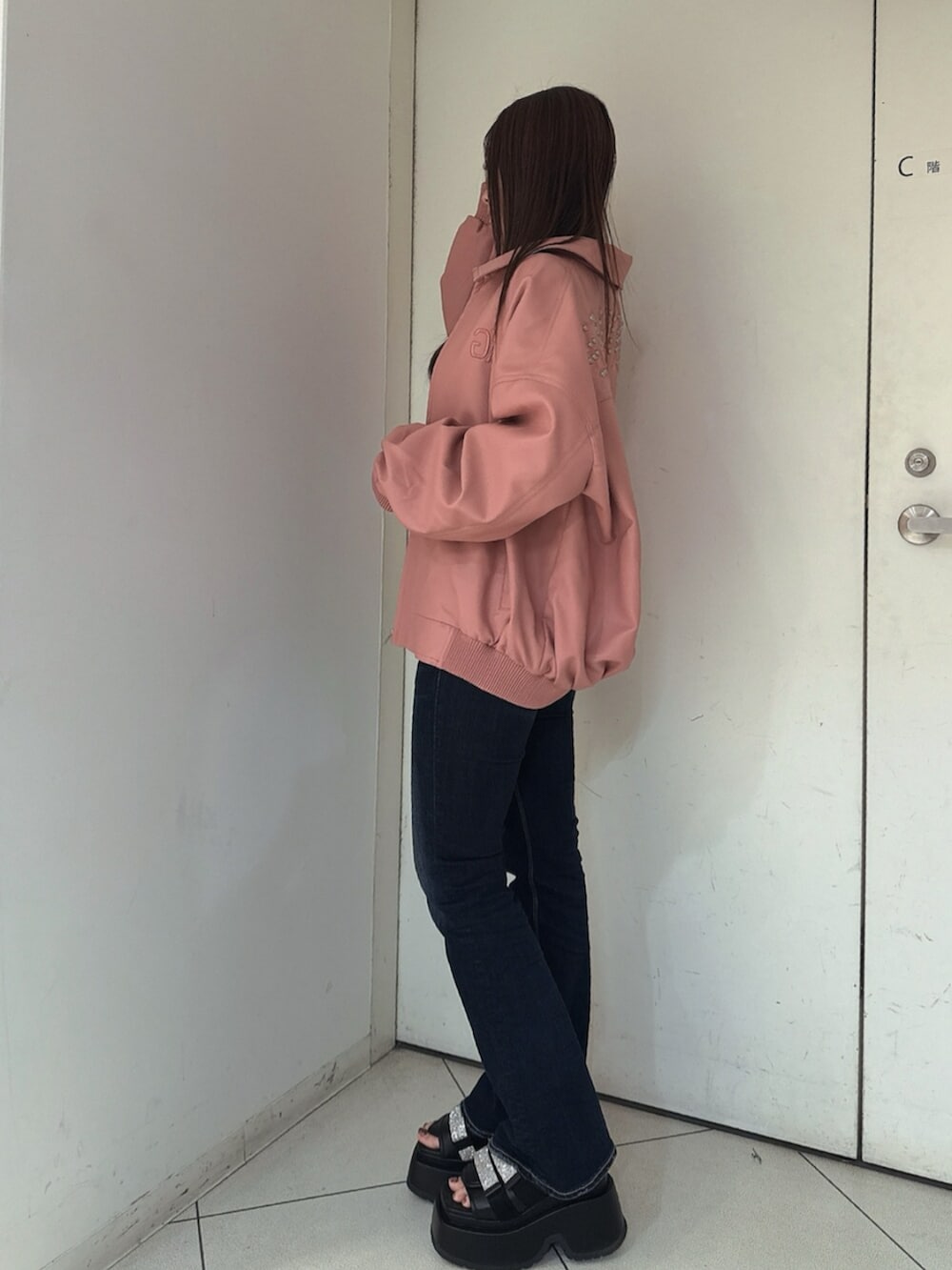 ブルー系のデニムパンツ、ブラック系のサンダル、ピンク系のブルゾンを着用したレディースの春コーディネートの2枚目の写真