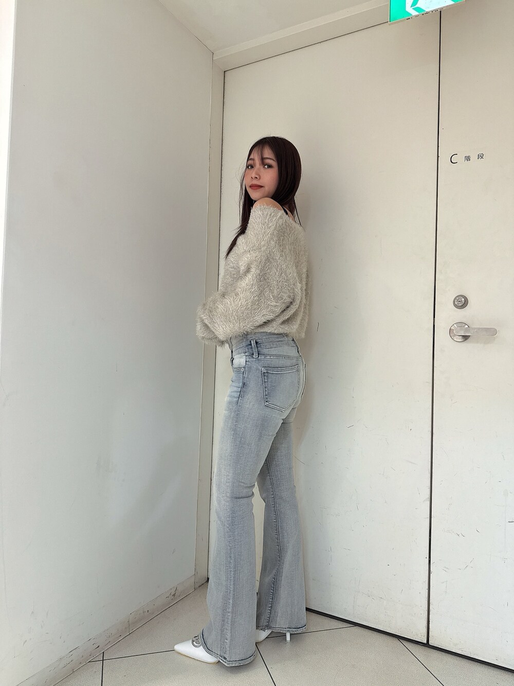 ブルー系のデニムパンツ、ホワイト系のパンプス、ベージュ系のカーディガン/ボレロを着用したレディースの秋コーディネートの2枚目の写真