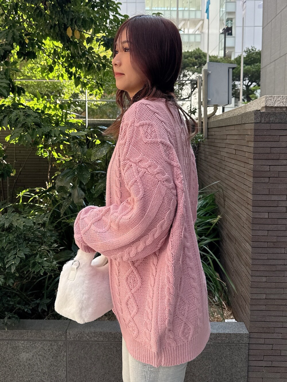 ピンク系のニット/セーター、ホワイト系のハンドバッグ、ブルー系のデニムパンツを着用したレディースの秋コーディネートの5枚目の写真