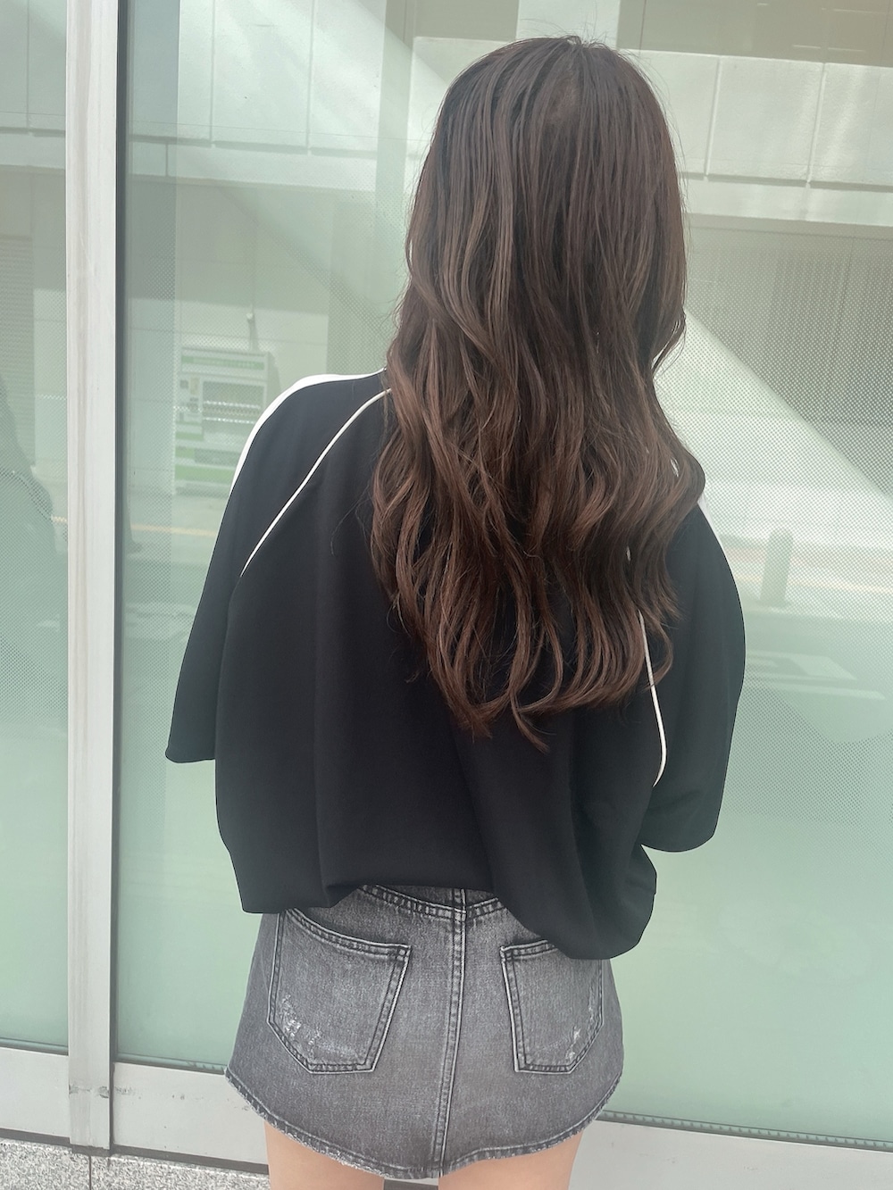 ブラック系のデニムスカート、ブラック系のTシャツ/カットソー、ブラック系のサンダルを着用したレディースの夏コーディネートの6枚目の写真