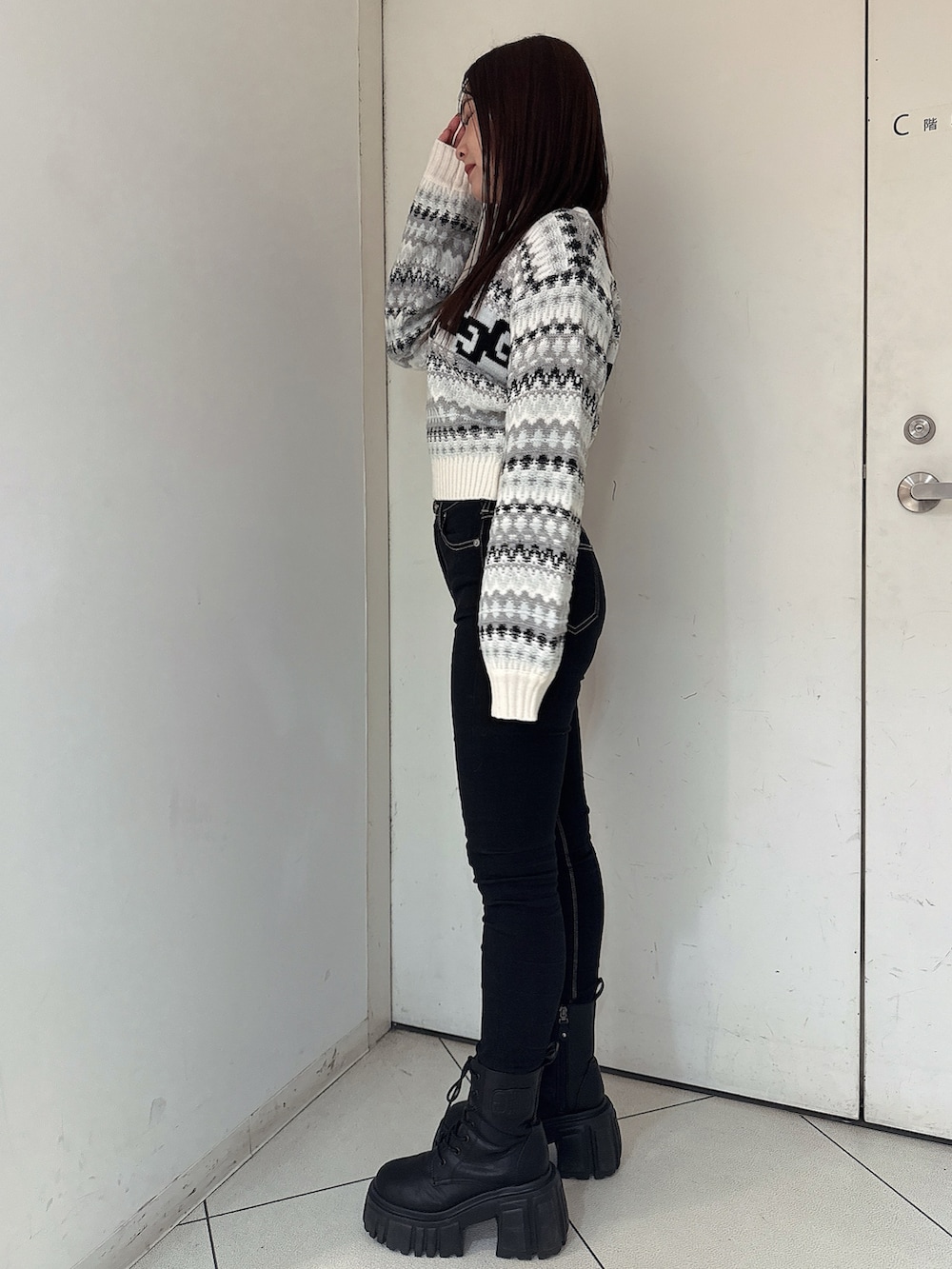 ブラック系のデニムパンツ、ブラック系のブーツ、ホワイト系のニット/セーターを着用したレディースの秋コーディネートの2枚目の写真