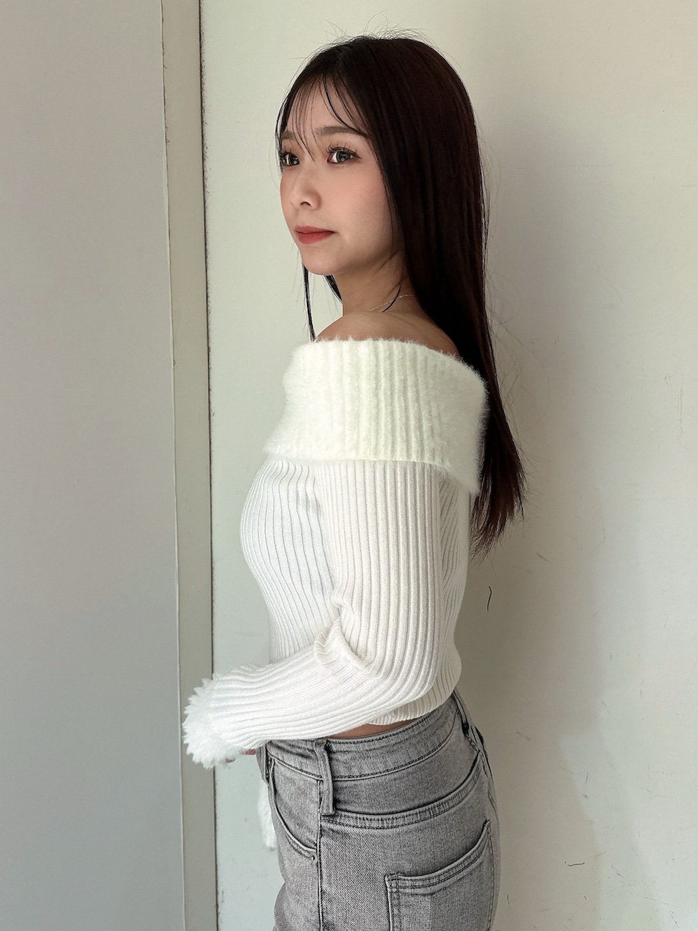 グレー系のデニムパンツ、ブラック系のブーツ、ホワイト系のニット/セーターを着用したレディースの冬コーディネートの5枚目の写真