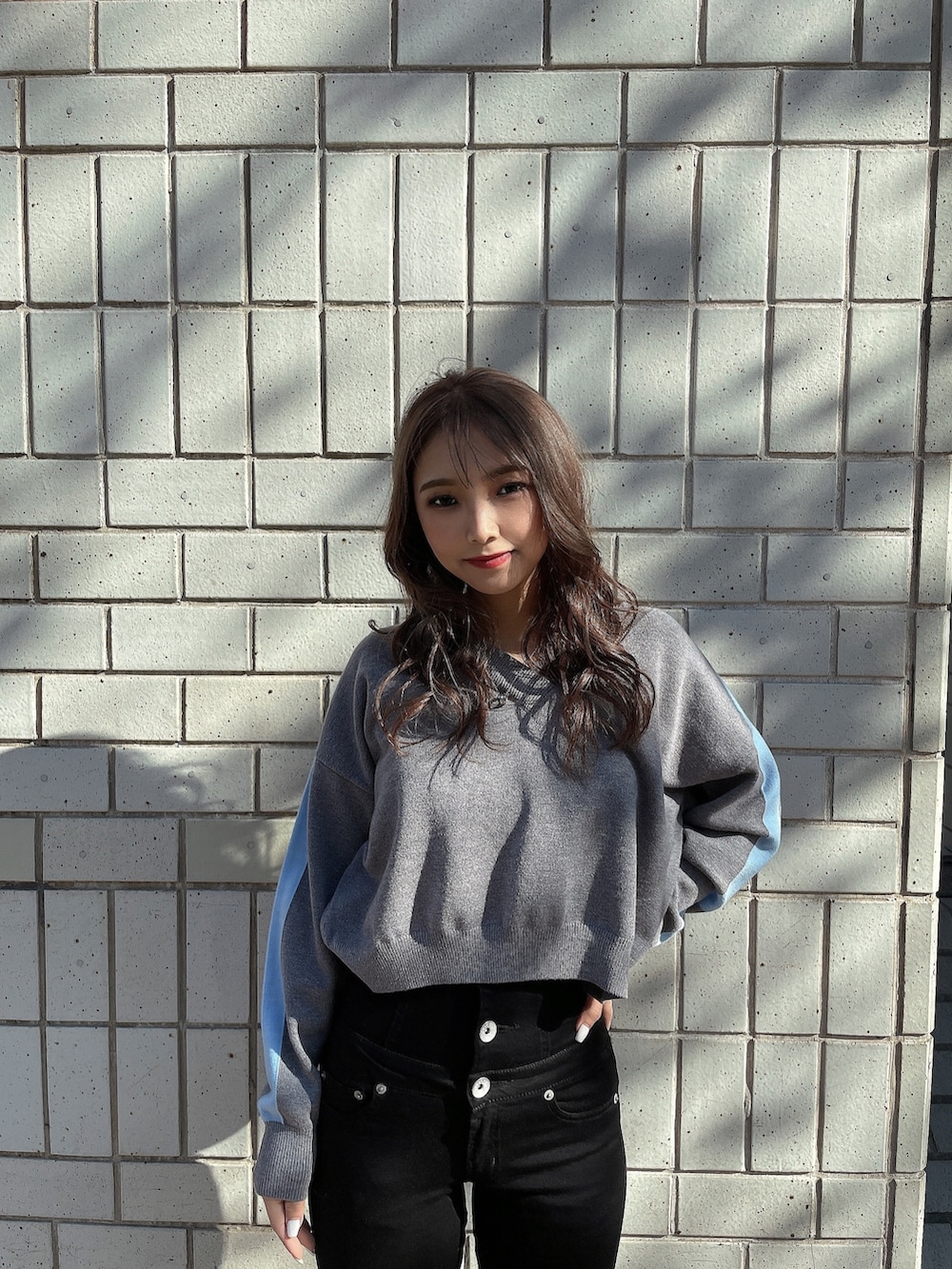 グレー系のニット/セーター、ブラック系のキャミソール、ブラック系のデニムパンツを着用したレディースの冬コーディネートの2枚目の写真