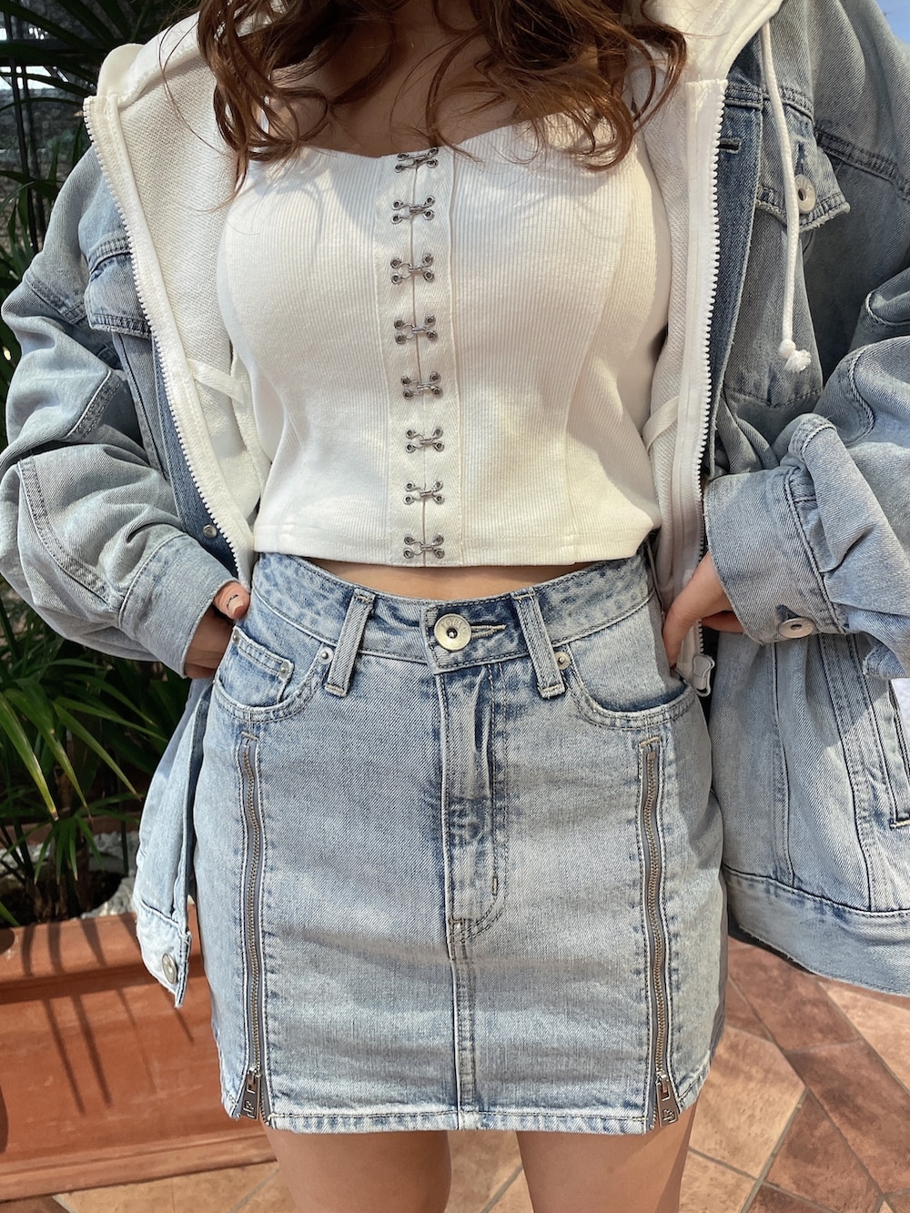 ホワイト系のキャミソール、ホワイト系のパーカー、ブルー系のデニムジャケットを着用したレディースの春コーディネートの6枚目の写真