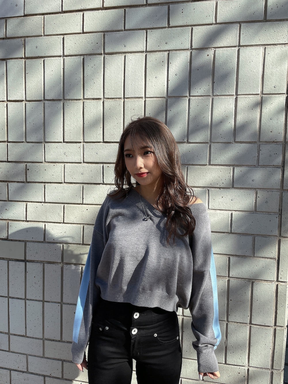 グレー系のニット/セーター、ブラック系のキャミソール、ブラック系のデニムパンツを着用したレディースの冬コーディネートの3枚目の写真