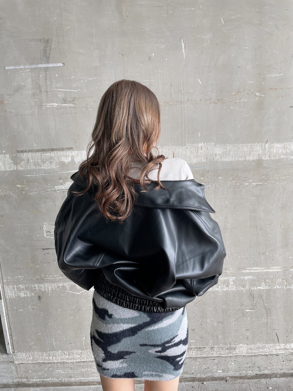 ブラック系のブルゾン、ホワイト系のニット/セーター、グレー系のスカートを着用したレディースの秋コーディネートの5枚目の写真