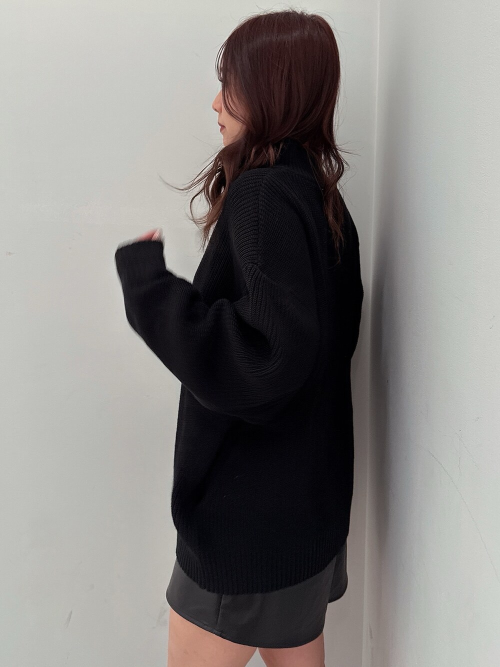 ブラック系のスカート、ブラック系のニット/セーター、ブラック系のブーツを着用したレディースの冬コーディネートの5枚目の写真